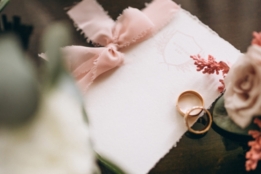 Picture of a wedding invitation with a pink ribbon and two rings on top of it in Contra Costa County