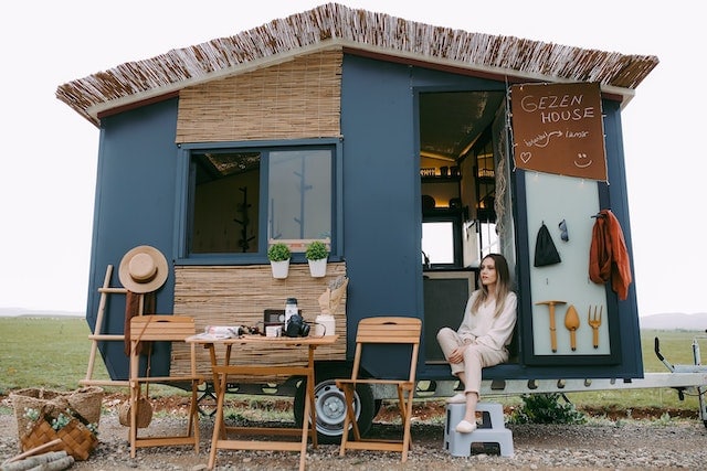 Woman sitting in tiny house on wheels for are tiny homes legal in california